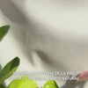 Primer plano de una mano que dispensa unas finas gotas de sérum peeling translúcido y ligero sobre las yemas de los dedos, masajeándolas suavemente sobre la piel limpia del rostro — su textura sedosa y fluida disuelve visiblemente células muertas, refina la textura cutánea y realza el brillo gracias a AHAs naturales (Lime Pearl), niacinamida y aceite de árbol de té 